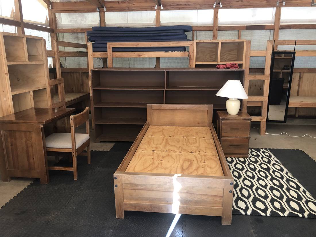 Inside a tent cabin — bed frame, mattress, desk, and shelving