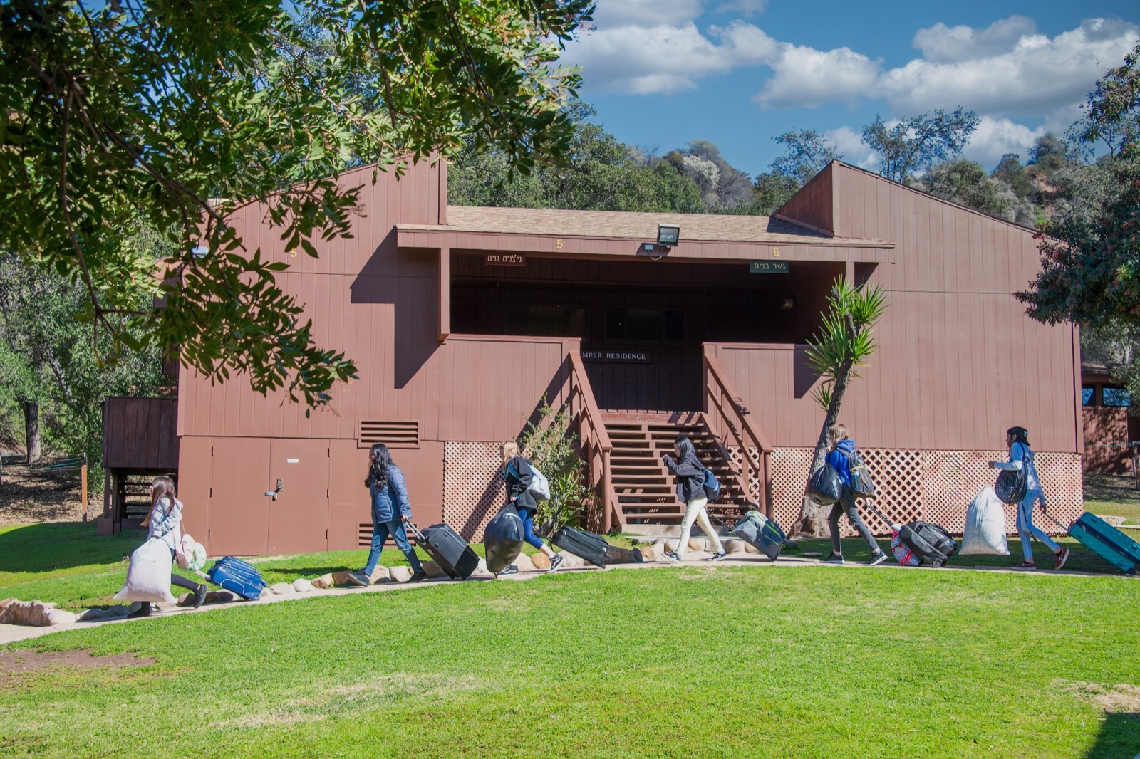 Students arriving at a Camp Ramah cabin with luggage on move-in day