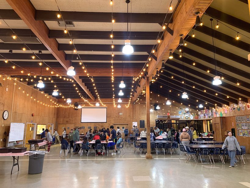 Staff and students gathered under string lights in the Camp Ramah dining hall